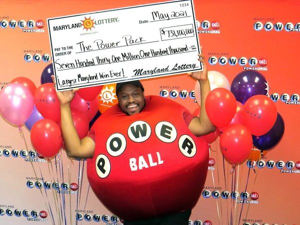Man in Red Power Ball Outfit Holding Cheque for The Power Pack