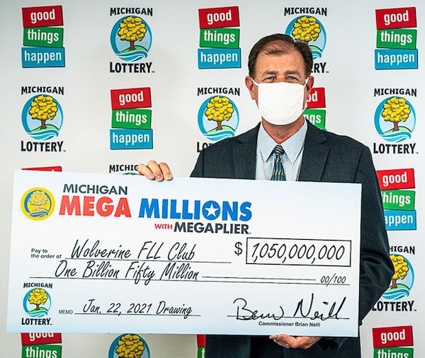 Man in Medical Mask Holding Oversized Cheque for Wolvering FLL Club