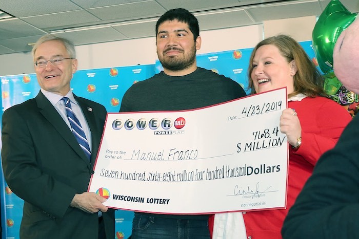 Manuel Franco holding up novelty check with lottery officials